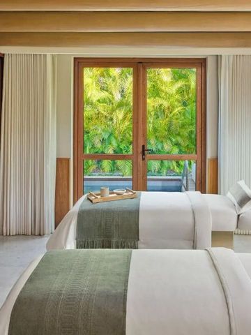 Luxuriöser Spa-Behandlungsraum mit zwei Liegen und Gartenblick.