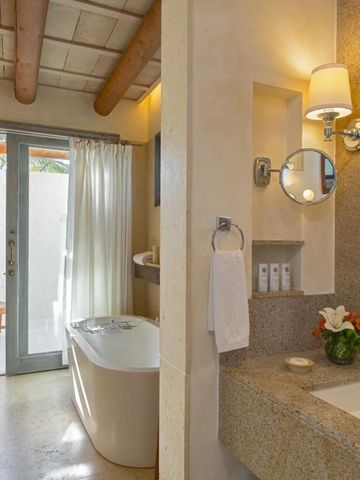 Luxuriöses Badezimmer mit Badewanne und Zugang zu einem privaten Außenbereich mit Pflanzen.