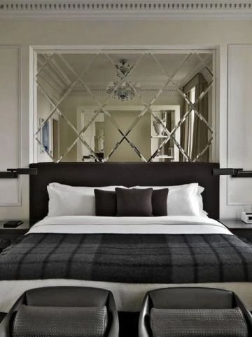 Elegantes Schlafzimmer in neutralen Tönen mit einem großen Bett und einem Spiegel im Hintergrund.