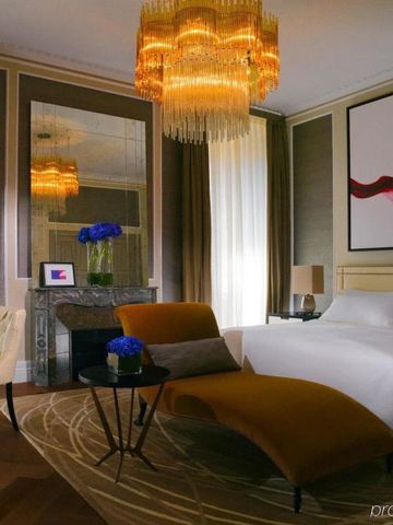 Opulentes Schlafzimmer mit Kronleuchter, Kamin und künstlerischem Gemälde an der Wand.