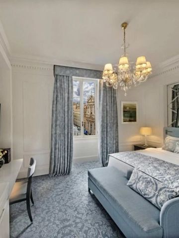 Zimmer mit klassischem Dekor, Blick auf die Stadt und luxuriöser Bettwäsche.