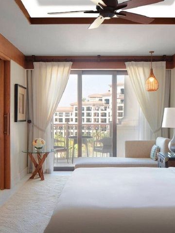 Helles Zimmer mit großem Bett, Deckenventilator und Blick auf den Balkon.