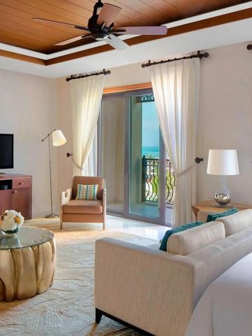 Geräumiges Hotelzimmer mit Sofa, Flachbildfernseher und privatem Balkon mit Meerblick