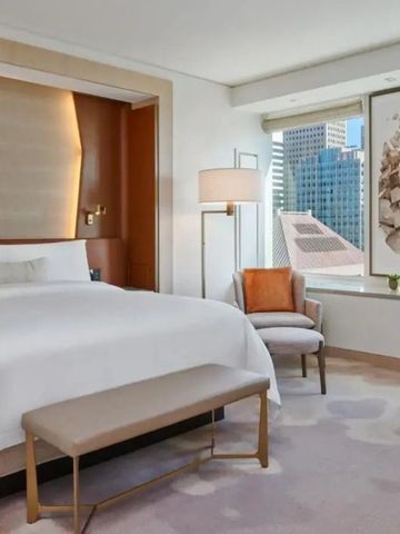 Geräumiges Hotelzimmer mit Kingsize-Bett und großen Fenstern mit Stadtblick.