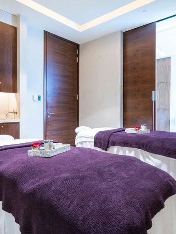 Zwei Massageliegen mit lila Decken in einem hellen Spa-Raum