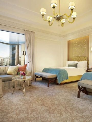 Helles Zimmer mit zwei Betten, eleganten Polstermöbeln und großen Fenstern