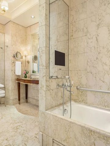 Helles Marmorbadezimmer mit Badewanne und großer Spiegelwand