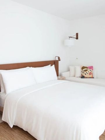 Helles Hotelzimmer mit großem Bett weißen Kissen und minimalistischer Einrichtung