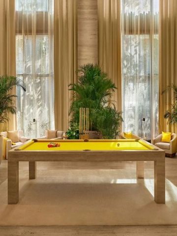 Luxuriöser Billardraum mit hohen Fenstern und Pflanzen