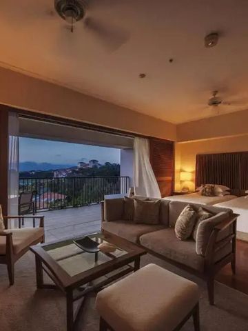 Elegantes Hotelzimmer mit Balkon und Blick auf das Meer bei Abenddämmerung