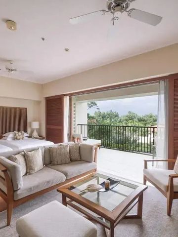 Helles Hotelzimmer mit zwei Betten, Sitzecke und großem Balkon mit Aussicht.