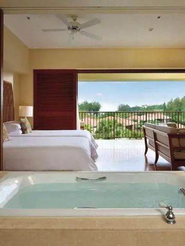 Hotelzimmer mit Badewanne neben zwei Betten und Balkon mit Gartenblick.