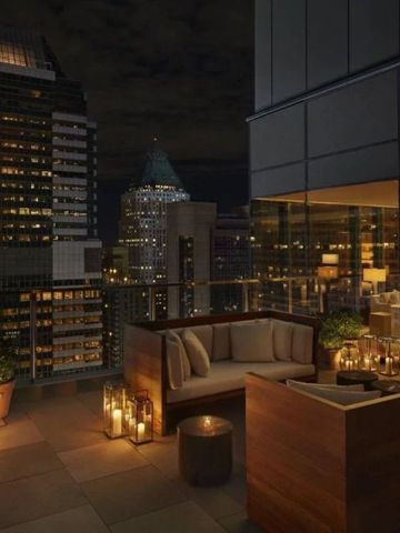 Gemütliche Dachterrasse des Hotels mit Blick auf New York bei Nacht.