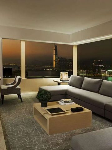 Geräumige Hotelsuite mit Panoramafenster und atemberaubendem Stadtblick bei Nacht.