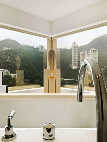 Luxuriöses Badezimmer mit freistehender Badewanne und Aussicht auf grüne Hügel.