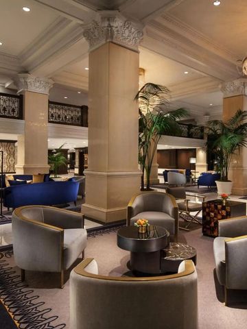 Elegante Hotellobby mit großen Säulen, luxuriösen Sesseln und glitzerndem Kronleuchter.