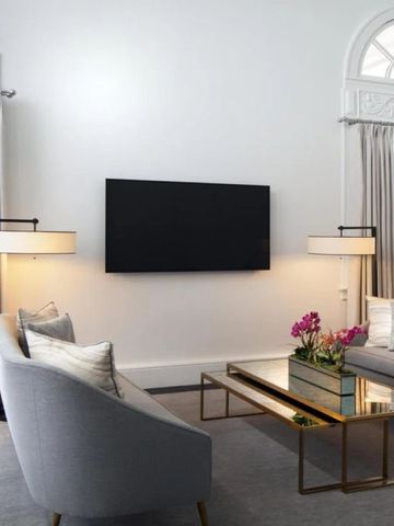 Luxuriöser Wohnbereich mit grauem Sofa, stilvollen Lampen und großem Fernseher.