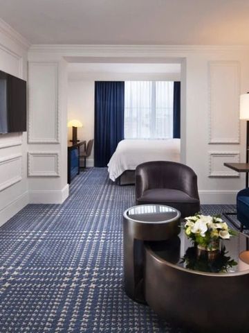 Geräumiges Hotelzimmer mit Schlafbereich und moderner Sitzecke in blauen Tönen