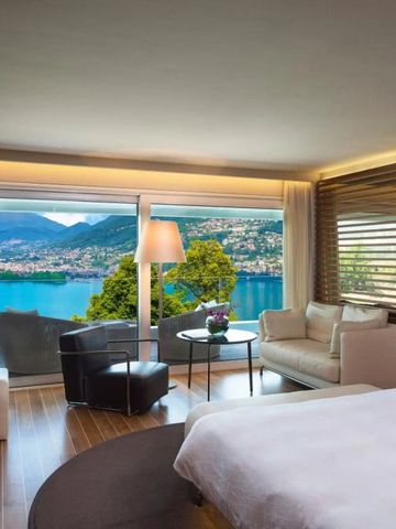 Zimmer mit Panoramafenster und Seeblick bei Tag.