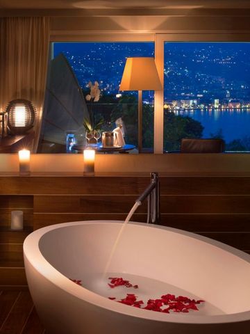 Elegante Badewanne mit Blick auf den See bei Nacht im luxuriösen Hotelzimmer