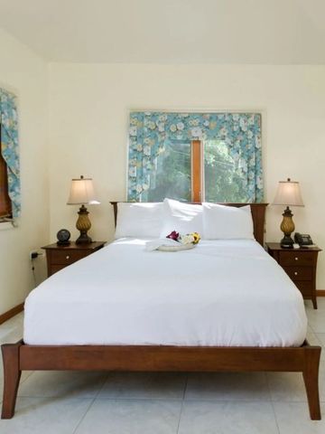 Gepflegtes Schlafzimmer mit weißem Doppelbett und blumiger Dekoration