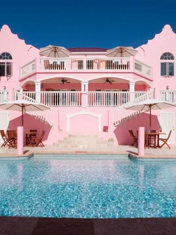 Elegante rosafarbene Villa mit Balkon und großem Pool im Vordergrund