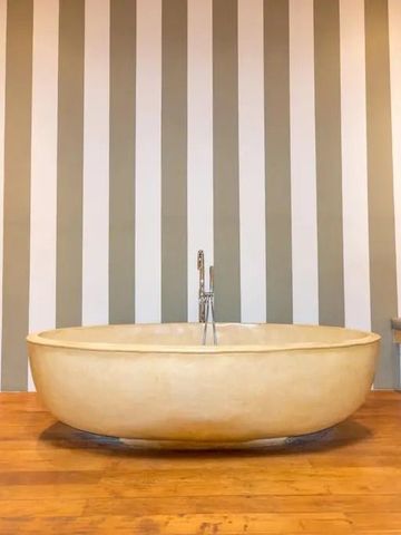 Luxuriöses Badezimmer mit freistehender runder Badewanne und gestreifter Wandtapete