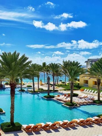 Großer Außenpool mit Liegestühlen und Palmen unter blauem Himmel