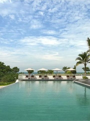 Infinity Pool mit Palmen und Liegestühlen unter blauem Himmel