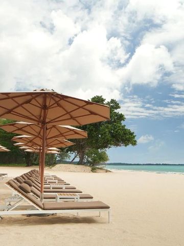 Sonnenliegen und Sonnenschirme am Sandstrand mit Blick auf das Meer