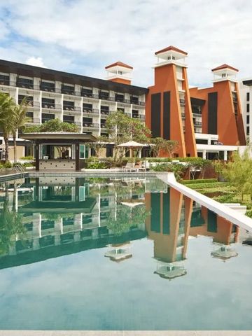 Hotelgebäude mit Pool und Palmen im Vordergrund