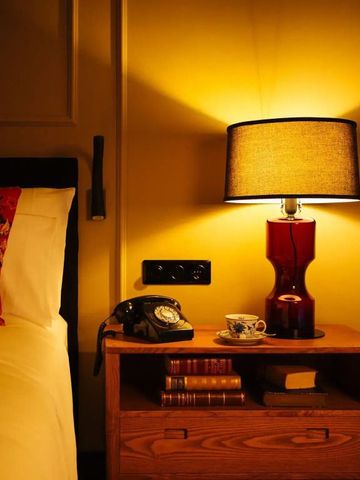 Nachttisch mit stilvoller Lampe und Vintage-Telefon im Hotelzimmer