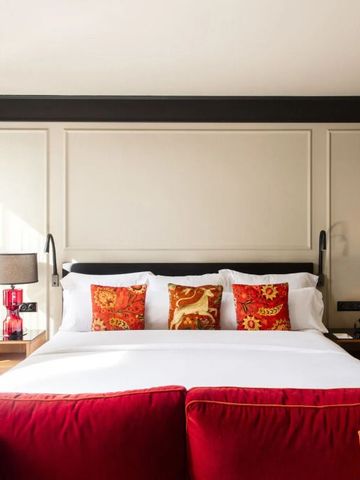 Luxus-Schlafzimmer mit rotem Sofa und dekorativen Kissen