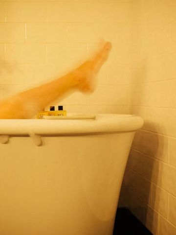 Bein in einer freistehenden Badewanne mit warmem Licht