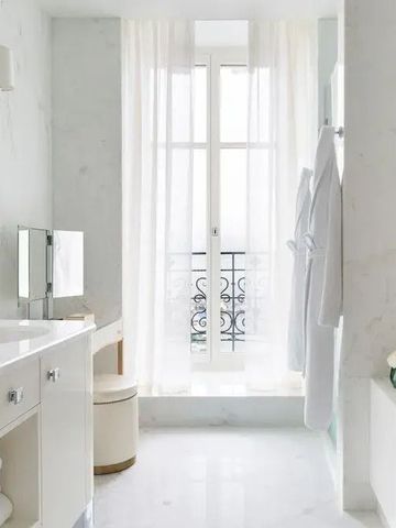 Modernes Badezimmer in Weiß mit großem Fenster und stilvollen Armaturen