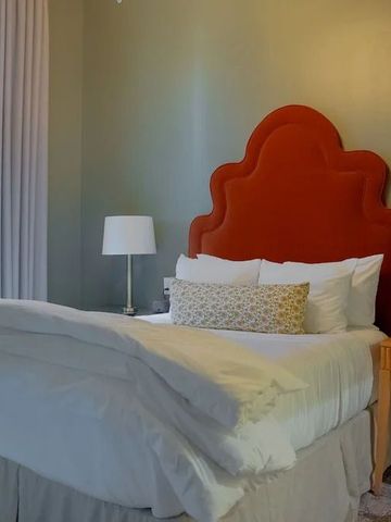 Gemütliches Zimmer mit großem roten Kopfteil und Lampe.