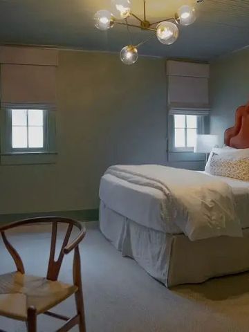 Geräumiges Zimmer mit moderner Beleuchtung und rotem Kopfteil.