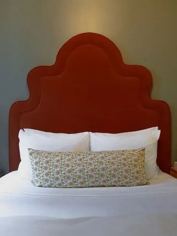 Bett mit rotem Kopfteil und dekorativen Kissen.