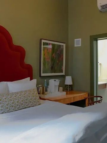 Elegant eingerichtetes Hotelzimmer mit rotem Kopfteil und Schreibtisch