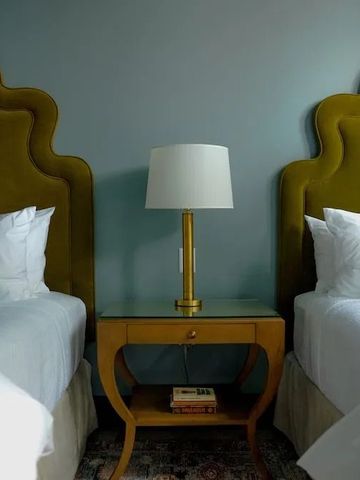 Zwei Einzelbetten mit goldenen Kopfteilen und einem stilvollen Nachttisch