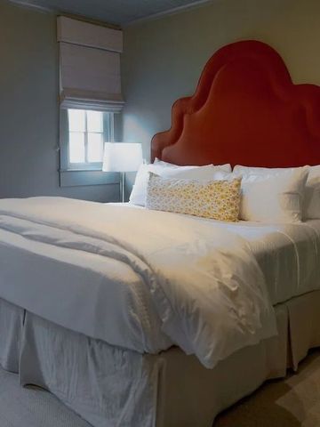 Komfortables Bett mit rotem Kopfteil in einem geschmackvoll eingerichteten Zimmer