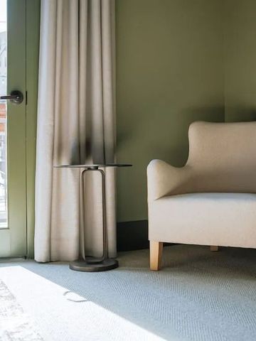 Helles Eckzimmer mit Sessel und kleinem Tisch nahe Balkontür