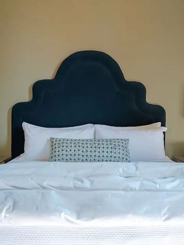 Luxuriöses Bett mit stilvollem Kopfteil und Kissen, symmetrisch angeordnet