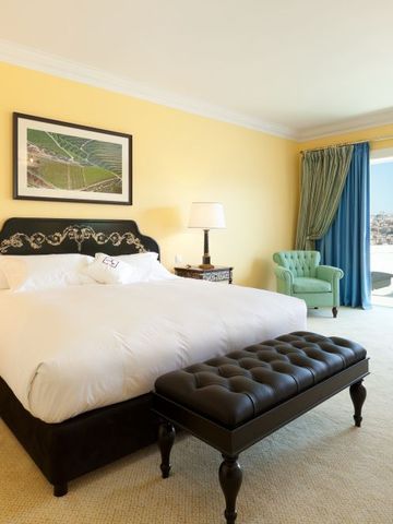 Helles Hotelzimmer mit großem Bett und Zugang zu Balkon mit Stadtblick.