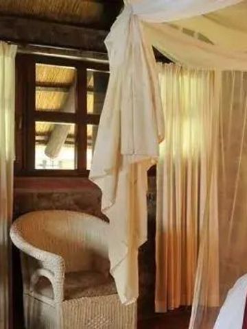 Komfortables Schlafzimmer mit Korbstuhl und großzügigen Fensterfronten