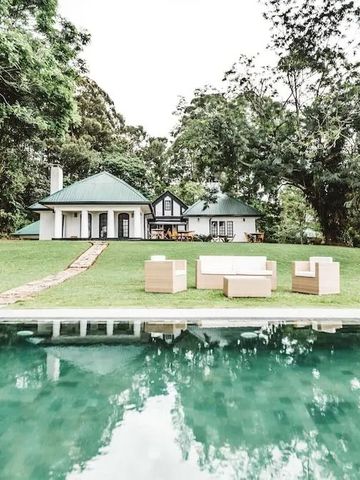 Luxusvilla mit Grünflächen und Pool in bewaldeter Umgebung.