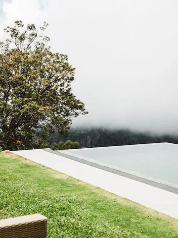 Infinity Pool mit Blick auf neblige Berge und grüne Landschaft.