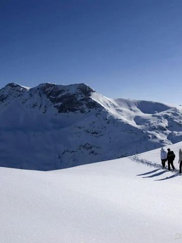 Verschneite Berglandschaft mit Wanderern unter klarem Himmel