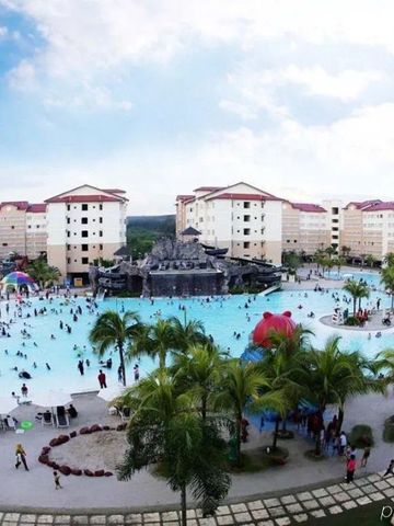 Großer Poolbereich mit Palmen und zahlreichen Gästen