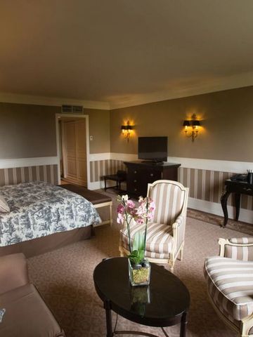 Großzügiges Zimmer mit eleganten Sitzmöbeln und Blumenarrangement